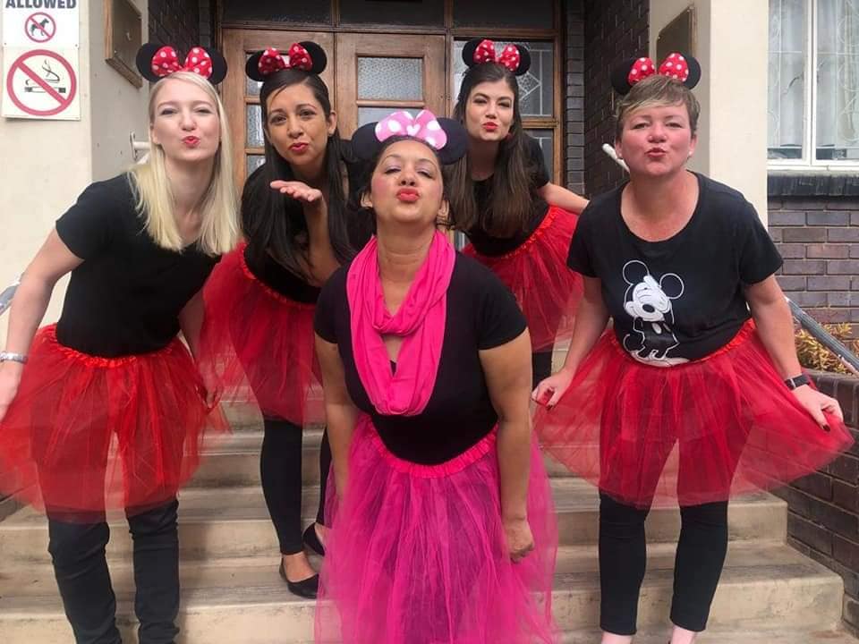 Group of ladies dressed in black with pink/red net tutu skirts, Minnie ears and posing for the cameraears and